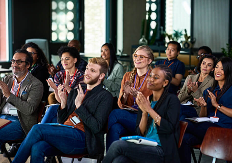 A diverse group seated at a conference applauding