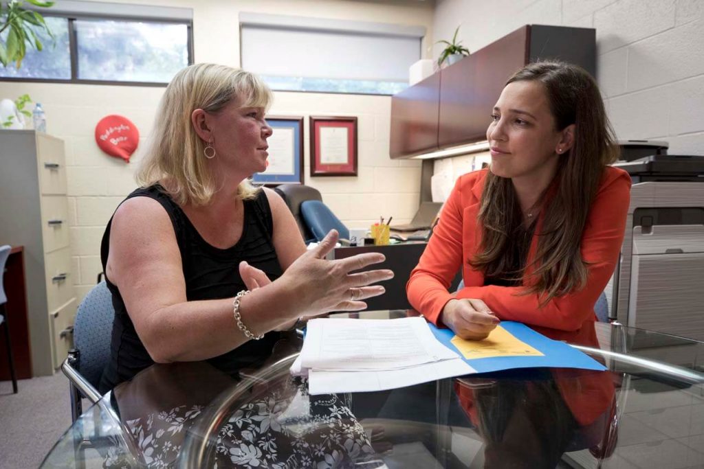 photo of 2 women seated at a table planning and talking together