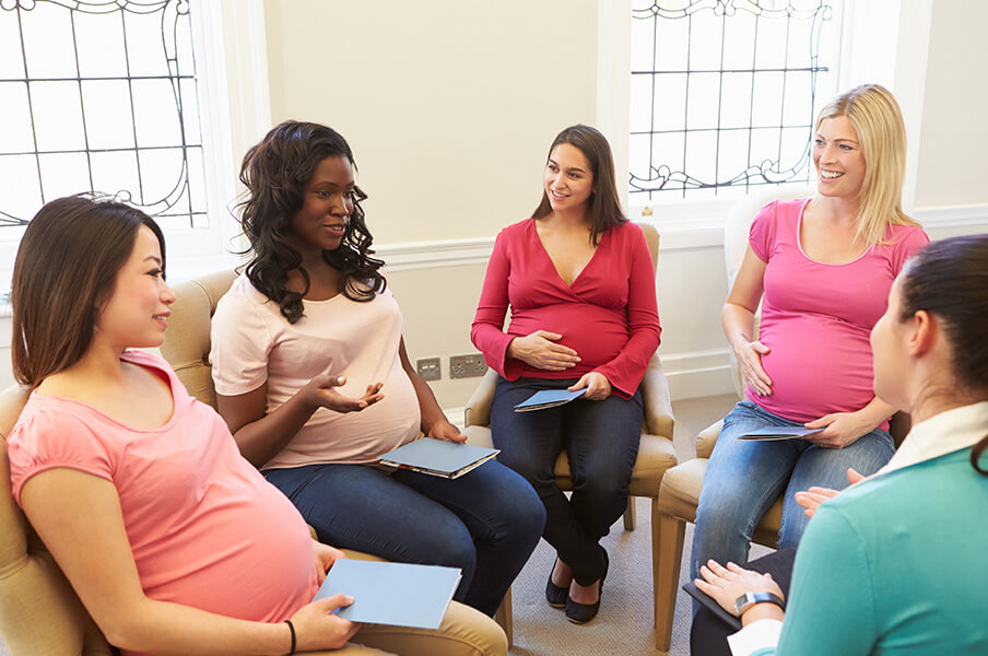 A diverse group of pregnant women sitting in a circle for a prenatal workshop with a nurse