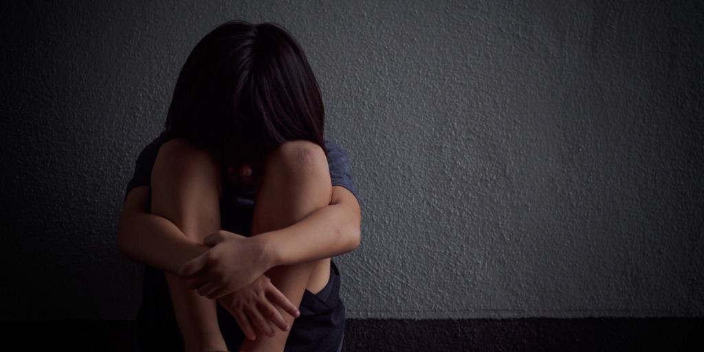 Young child with head in knees sitting against a wall grief and bereavement