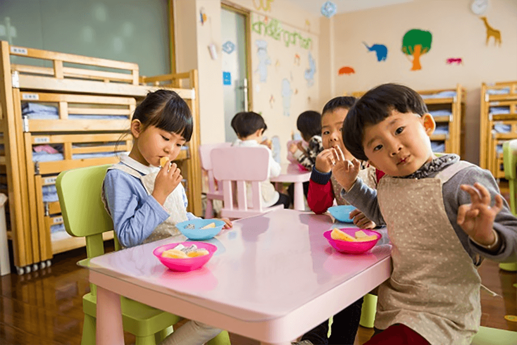 Asian kindergarten children at a table eating a snack