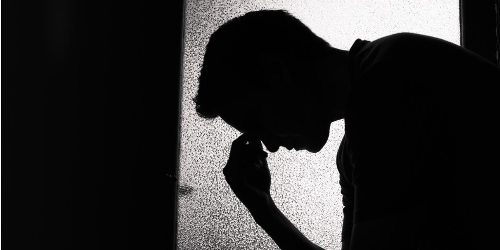 shadow of a person with head down looking sad