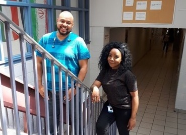 Samantha and Stephen, two youth outreach workers standing on stairs in a high school