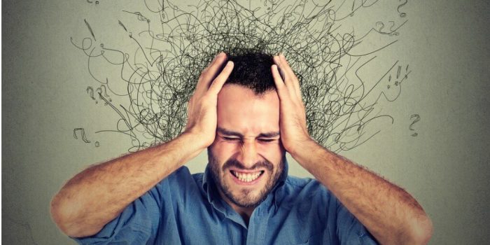 person holding head with many thoughts weighing them down need for CBT for anxiety