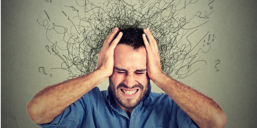 person holding head with many thoughts weighing them down need for CBT for anxiety