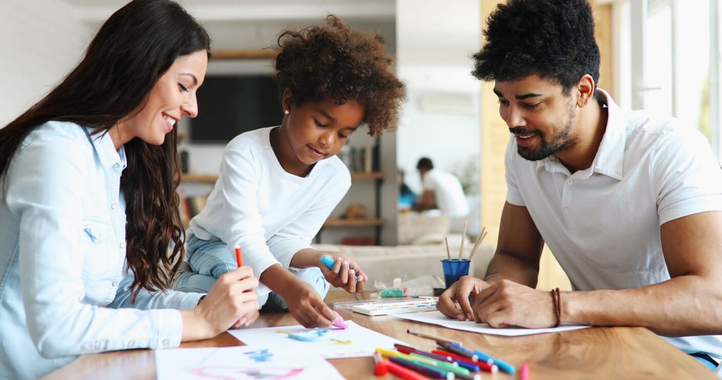 adults at a table doing art with a child