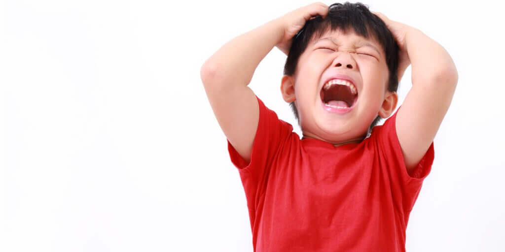 child with eyes closed and yelling/screaming with hands on head