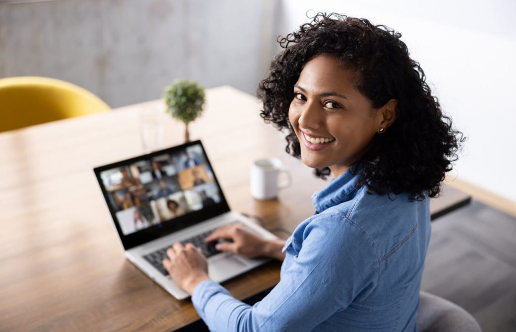 person sitting at computer turning over shoulder to smile at camera