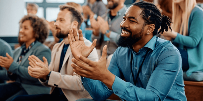 Group of professionals engaged and clapping at a presentation for high impact presentation skills training