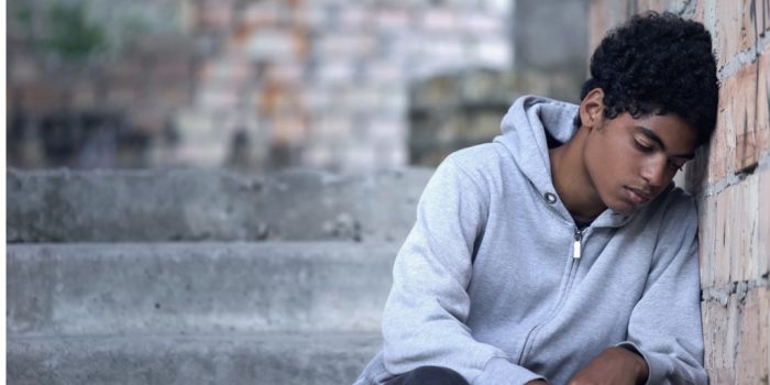 youth sitting alone with head leaning on wall looking sad depression in youth