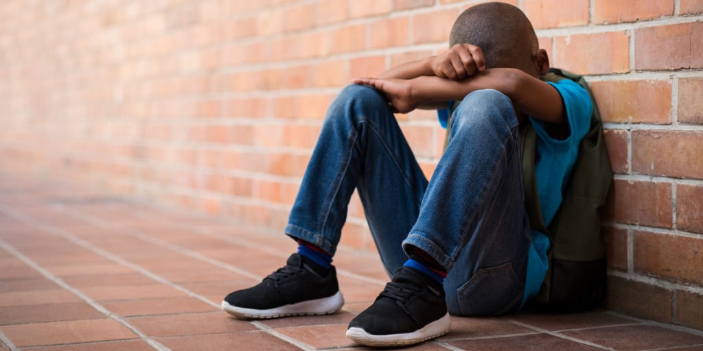 boy wearing a backpack with head down for CBT for school avoidance and refusal