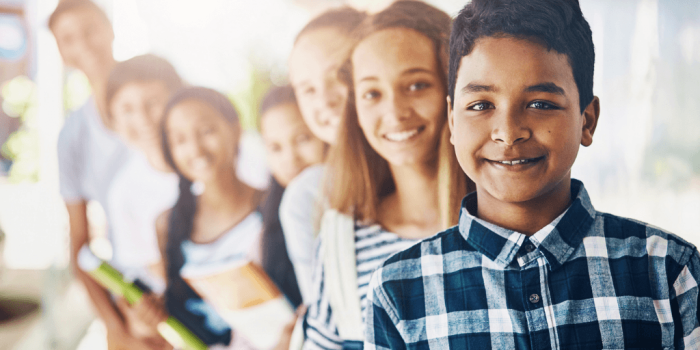 group of school aged students in a line from smallest to biggest smiling a camera